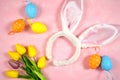 Easter creative composition with bunny ears and easter eggs on pink background.