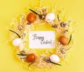 Easter creative concept. Wreath of white, brown chicken eggs, quail eggs, flowers and greeting card with inscription Happy Easter Royalty Free Stock Photo