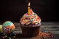 Easter cupcake with burning candle and chocolate eggs on wooden background, A Happy birthday cupcake with so many sweet toppings