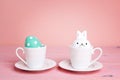 Easter cups with egg and bunnny on a pink table. Royalty Free Stock Photo