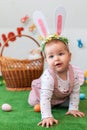 Easter. Cute little girl with rabbit ears, posing on an artificial lawn. In the background, a basket and eggs. Vertical Royalty Free Stock Photo