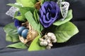 Easter deco with flowers and leaves. Black background image. Blue eggs on nest.