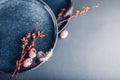 Easter decor. Close up of dishes with eggs, feathers and spring branches. Ceramic plates on grey background. Space Royalty Free Stock Photo
