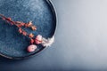 Easter decor. Close up of dishes with eggs, feathers and spring branches. Ceramic plates on grey background. Space Royalty Free Stock Photo