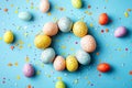Easter decor with colorful eggs in a circle and confetti on a bright blue background. Copy space Royalty Free Stock Photo