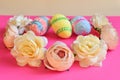 Easter decor. Decorated eggs and wreath of flowers on bright pink background. Close-up of multi colored easter flowers and eggs Royalty Free Stock Photo