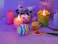 Easter decor, painted eggs, paints, brushes, lighted pink candles on a lilac background, preparation for the Easter holiday