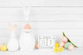 Easter decor on a white shelf against a white wood panel background