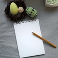 Easter decorated eggs in nest, blank paper notepad on grey background