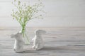 Easter decoration. Ceramic white bunnies on white wooden table with fresh white spring flowers