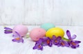 Easter decoration. Easter colored easter eggs and violet flowers crocuses on white wooden table. Top view, flat lay Royalty Free Stock Photo