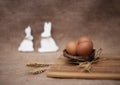 Easter decoration with eggs in the nest with spikes of wheat on bright board and two rabbits on sackcloth background Royalty Free Stock Photo