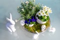 Easter decoration for the garden table, Easter bunny, bunnies, spring flowers, white primroses, blue pansies, daisies, Easter eggs Royalty Free Stock Photo