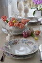 Easter decoration: laid table with dishes decorated with colored eggs and pink tulips. Royalty Free Stock Photo