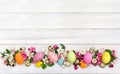 Easter decoration. Pink flowers apple tree and colored easter eggs and quail eggs on background of white painted wooden planks