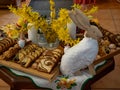 Easter decoration with rabbits and plates with tasty cake and fruit