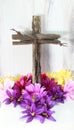 Handmade cross from wood, with barb wire with easter bright flowers at the bottom of cross base