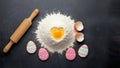 Easter decorations: gingerbread in the form of Easter eggs, fresh flour with a broken raw egg in the shape of a heart. Royalty Free Stock Photo