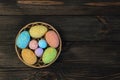 Easter decorative eggs in a basket on a brown background from boards. Royalty Free Stock Photo