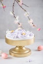 Easter dessert table. Pavlova mini nests with candy eggs and a flowering branches on white background. Side view. Easter greeting
