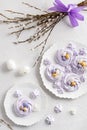 Easter dessert table. Pavlova mini nests with candy eggs and a willow bouquet on white background. Top view. Easter greeting card