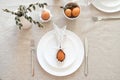 Easter dinner table setting with egg in Easter bunny napkin on plate, fork and knife, willow on linen tablecloth. Flat lay, top Royalty Free Stock Photo