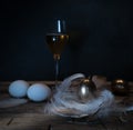 Easter. Easter night. Golden and White eggs, glass of wine, feathers on a wooden table. Vintage. Dark background Royalty Free Stock Photo