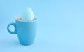 Easter egg in cup on blue background with empty space for text Royalty Free Stock Photo