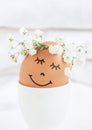 Easter egg with cute face in floral wreath crowns in egg cup on white background Royalty Free Stock Photo