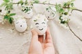 Easter egg with drawn cute face in floral wreath in person hand on background of eggs and petals Royalty Free Stock Photo