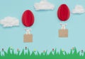 Easter egg hot air balloons made of paper with bunnies fly in the blue sky with cotton clouds over green grass and flowers. Happy Royalty Free Stock Photo