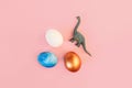 Easter egg hunt holiday composition, colorful eggs with dinosaur on light pastel pink backgroind. Seasonal spring kids Royalty Free Stock Photo