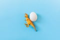 Easter egg hunt holiday composition, white eggs with dinosaur on light blue backgroind. Seasonal spring kids game