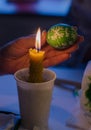 Easter egg in the master's hands above candle flame Royalty Free Stock Photo