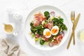 Easter egg salad with prosciutto and broccolini on white background, top view. Easter salad with boiled egg Royalty Free Stock Photo