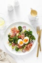 Easter egg salad with prosciutto and broccolini on white background, top view. Easter salad with boiled egg