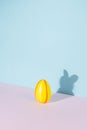 Easter egg with shadow in the shape of bunny or rabbit on pastel pink and blue background. Minimal Easter concept Royalty Free Stock Photo