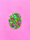 Easter egg shape made Multi-colored Sugar sprinkle dots, decoration for cake and bakery in pink background. Minimal Royalty Free Stock Photo