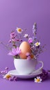 Easter egg and spring flowers in a cup of tea on a violet background, creative Easter holiday concept, minimalism for Royalty Free Stock Photo