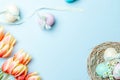 Easter eggs background. Colorful egg with tape ribbon, spring tulips, feathers on pastel blue background in Happy Easter Royalty Free Stock Photo