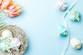 Easter eggs background. Colorful egg with tape ribbon, spring tulips, feathers on pastel blue background in Happy Easter Royalty Free Stock Photo