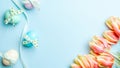 Easter eggs background. Colorful egg with tape ribbon, spring tulips, feathers on pastel blue background in Happy Easter Royalty Free Stock Photo