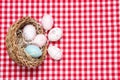 Easter eggs background. Top view on a wicker basket with colorful easter eggs on a red tablecloth or napkin. Decoration background Royalty Free Stock Photo