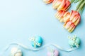 Easter eggs basket. Colorful egg with tape ribbon, spring tulips, white feathers on pastel blue background in Happy Easter Royalty Free Stock Photo