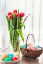 Easter eggs in a basket with red tulips in a vase Royalty Free Stock Photo