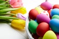 Easter eggs in basket and spring colorful flowers on white wooden table Royalty Free Stock Photo