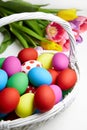 Easter eggs in basket and spring colorful flowers on white wooden table Royalty Free Stock Photo