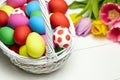 Easter eggs in basket and spring colorful flowers on white wooden table Royalty Free Stock Photo