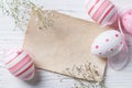 Easter eggs and blank note on wooden background, pastel colors, top view