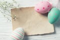 Easter eggs and blank note on wooden background, pastel colours, top view Royalty Free Stock Photo